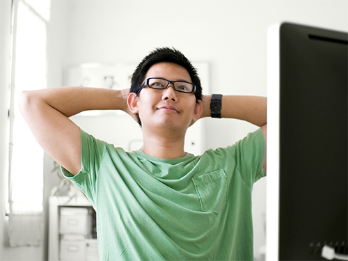 Photo: Young adult taking a break from work on the computer.