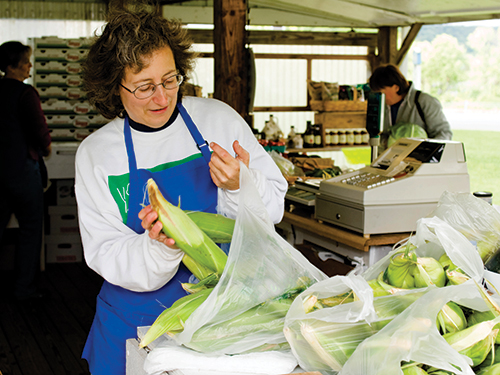 Photo: Person bagging vegetables on farmers market.