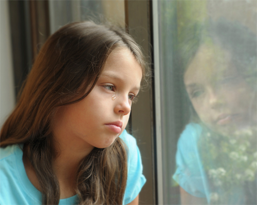 Photo: Girl looking out of a window.