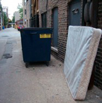 disposed off mattress near a dumpster