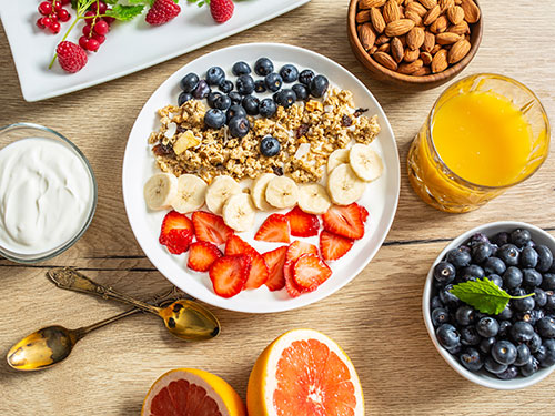 Photo: A bowl filled with cereal and strawberries surrounded by other healthy breakfast items.