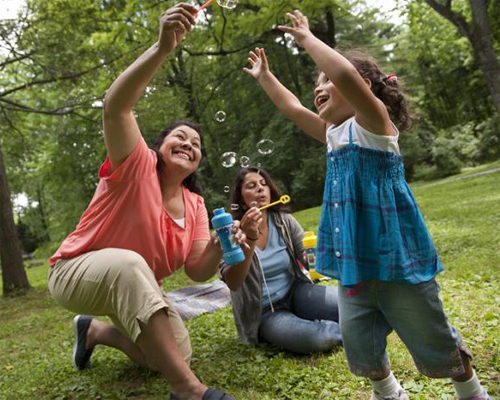 Photo: Adults and children playing with bubbles.
