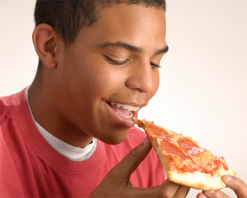 Photo: Young person enjoying a slice of pizza.