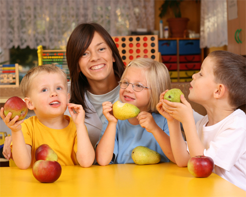 Photo: Teacher and three children eating pears and apples.