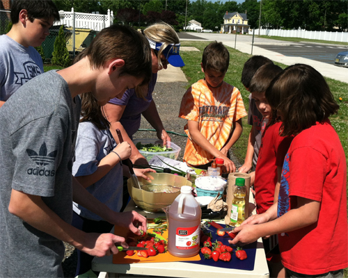 Photo: Children preparing food outdoors.