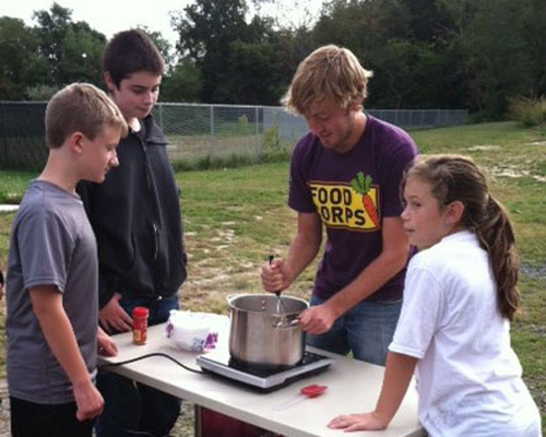 Photo: Students and teacher use a heated plate for cooking outdoorss.