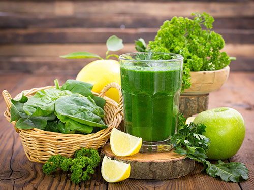 Photo: Green smoothie in a glass surrounded by green vegetables.