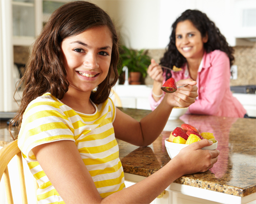 Photo: Mother and daughter smiling and eating breakfast.