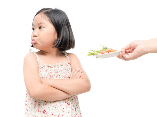 Photo: girl with expression of disgust against vegetables.