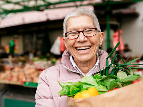 Senior person holding a paper bag filled with groceries.