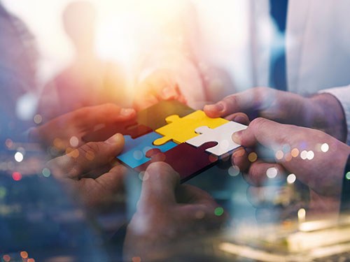 Hands assembling puzzle pieces.