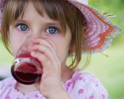 Photo: Little girl drinking a glass of juice.
