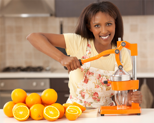 Photo: Woman sqeezing orange slices to making juice.