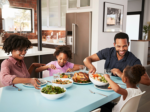 Photo: Family enjoying meal around table at home together.